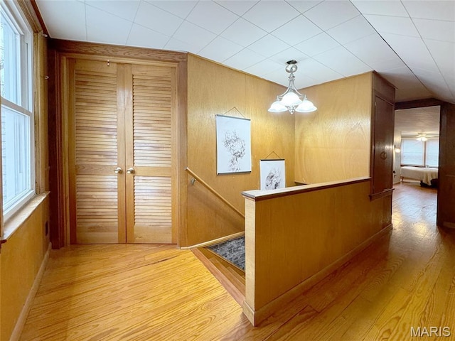 1001 Pike St, Saint Charles, MO 63301 - corridor with light wood finished floors, an upstairs landing, wooden walls, and a chandelier