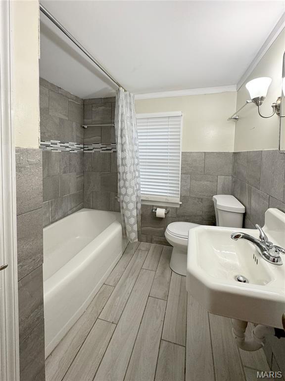 1001 Pike St, Saint Charles, MO 63301 - bathroom featuring tile walls, shower / tub combo, wood finish floors, ornamental molding, and a wainscoted wall