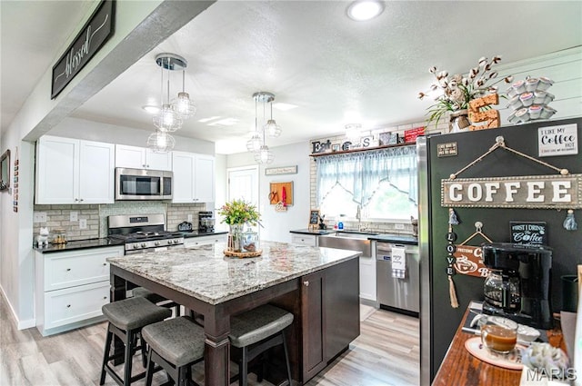 12310 State Route Hh, Rolla, MO 65401 - kitchen with stainless steel appliances, decorative backsplash, white cabinets, a kitchen island, and a textured ceiling
