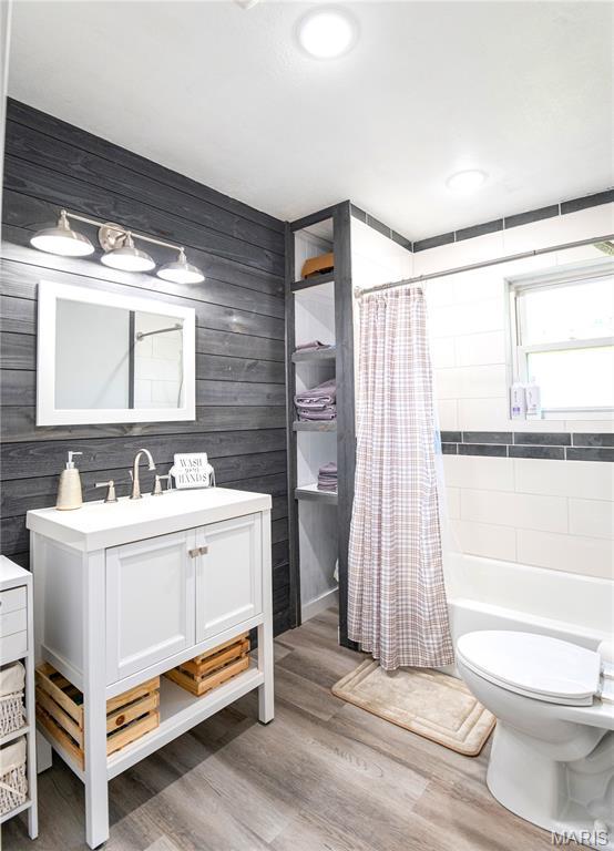 12310 State Route Hh, Rolla, MO 65401 - full bath featuring vanity, wood finished floors, toilet, shower / bath combination with curtain, and wooden walls