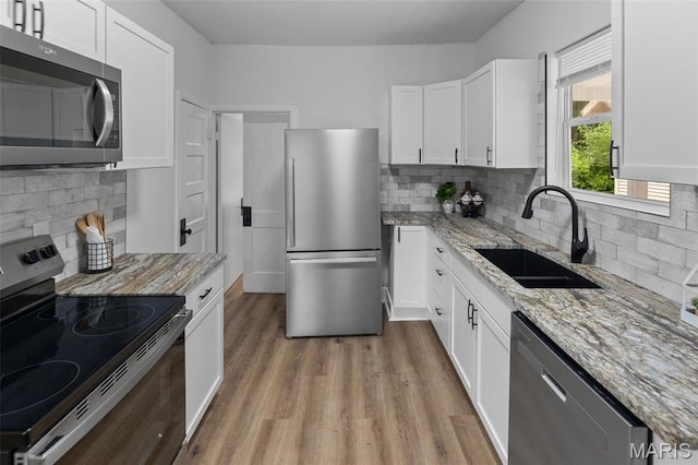 1801 Main St, Alton, IL 62002 - kitchen with stainless steel appliances, white cabinetry, light wood-style floors, and backsplash