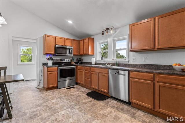 302 Bogy St, De Soto, MO 63020 - kitchen featuring appliances with stainless steel finishes, healthy amount of natural light, dark countertops, vaulted ceiling, and brown cabinetry