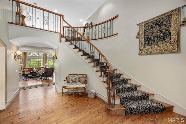 701 Crown Pointe Farms, Defiance, MO 63341 - staircase with arched walkways, wood finished floors, crown molding, recessed lighting, and a high ceiling