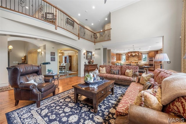 701 Crown Pointe Farms, Defiance, MO 63341 - living area with arched walkways, wood finished floors, high vaulted ceiling, a chandelier, and recessed lighting