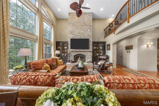 701 Crown Pointe Farms, Defiance, MO 63341 - living area featuring a high ceiling, a ceiling fan, a stone fireplace, crown molding, and arched walkways