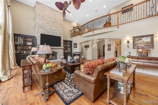 701 Crown Pointe Farms, Defiance, MO 63341 - living room with ceiling fan, arched walkways, wood finished floors, a high ceiling, and a fireplace