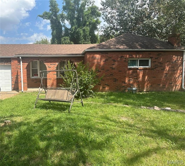 801 Howell Ave E, St Louis, IL 62206 - rear view of property featuring brick siding, a chimney, a yard, an attached garage, and roof with shingles