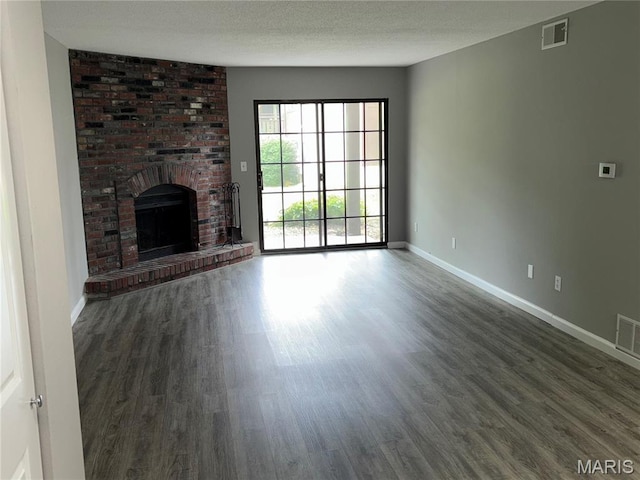 1420 Heritage Lndg Unit 107, Saint Charles, MO 63303 - unfurnished living room featuring wood finished floors, a brick fireplace, and a textured ceiling