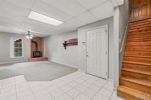 2518 Nike Base Rd, Catawissa, MO 63015 - unfurnished living room featuring a wood stove, stairs, a paneled ceiling, light colored carpet, and light tile patterned floors