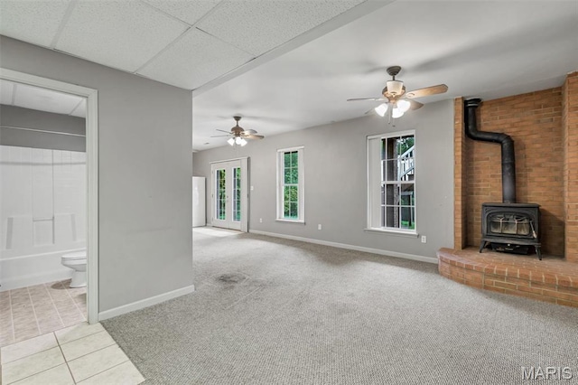 2518 Nike Base Rd, Catawissa, MO 63015 - unfurnished living room featuring a wood stove, a ceiling fan, tile patterned floors, and carpet floors
