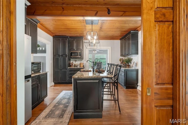 2466 State Road Ff, Eureka, MO 63025 - kitchen featuring appliances with stainless steel finishes, wooden ceiling, an island with sink, light stone countertops, and wood finished floors