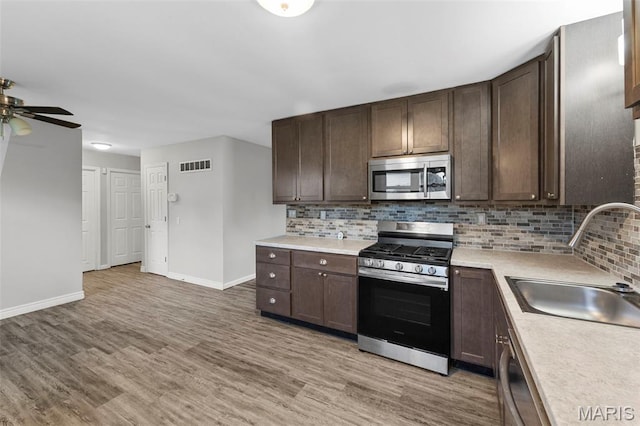 2185 Orleans Ln, Florissant, MO 63031 - kitchen featuring stainless steel appliances, light wood-style floors, and decorative backsplash