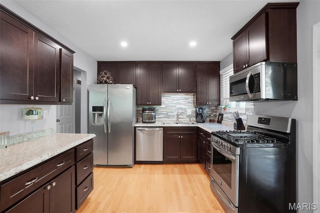 1809 Partridge Dr, Windsor Township, MO 63052 - kitchen with appliances with stainless steel finishes, light wood-type flooring, dark brown cabinetry, backsplash, and recessed lighting