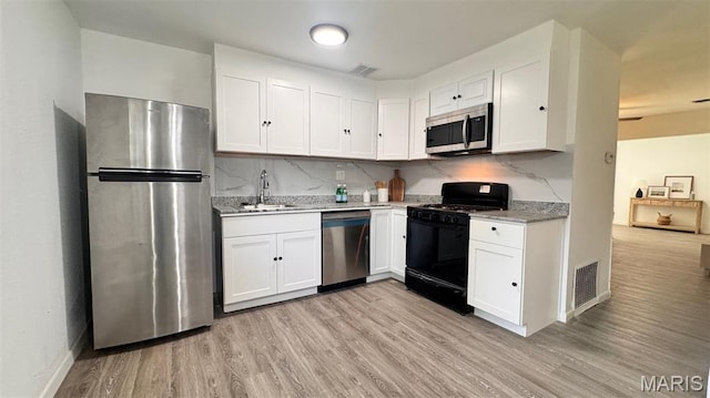 3553 Mckibbon Rd, Saint Louis, MO 63114 - kitchen with stainless steel appliances, white cabinets, light wood-style floors, and backsplash
