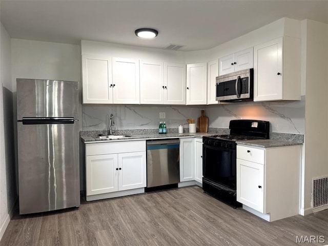 3553 Mckibbon Rd, Saint Louis, MO 63114 - kitchen featuring stainless steel appliances, white cabinets, light wood-style floors, and light stone counters