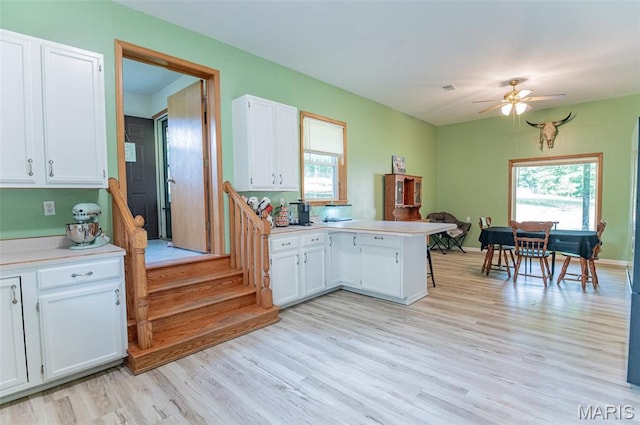 10201 County Road 5440, Rolla, MO 65401 - kitchen with a peninsula, white cabinets, light wood finished floors, and light countertops