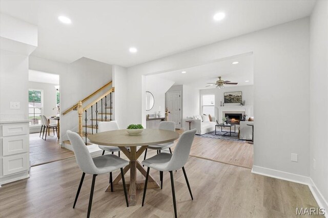 4507 Behlmann Grove Pl, Florissant, MO 63034 - dining space with stairs, a ceiling fan, light wood-style flooring, a lit fireplace, and recessed lighting