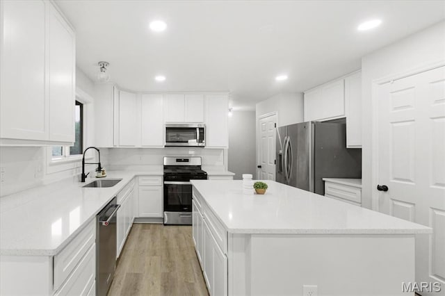 4507 Behlmann Grove Pl, Florissant, MO 63034 - kitchen with stainless steel appliances, a kitchen island, recessed lighting, white cabinets, and light wood-style floors