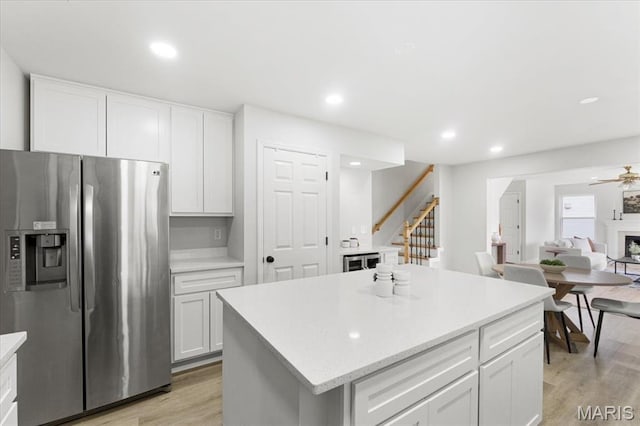 4507 Behlmann Grove Pl, Florissant, MO 63034 - kitchen with stainless steel refrigerator with ice dispenser, light wood finished floors, white cabinetry, a center island, and recessed lighting