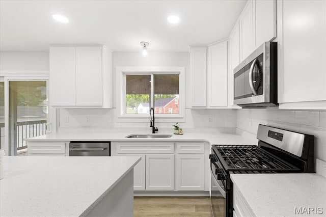 4507 Behlmann Grove Pl, Florissant, MO 63034 - kitchen featuring appliances with stainless steel finishes, white cabinets, recessed lighting, tasteful backsplash, and light wood-style floors