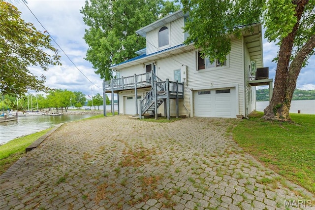 380 Yachtview Dr, West Alton, MO 63386 - view of front of house featuring an attached garage, stairs, a deck with water view, and decorative driveway