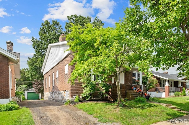 4950 Eichelberger St, Saint Louis, MO 63109 - obstructed view of property featuring an outbuilding, brick siding, and a front lawn