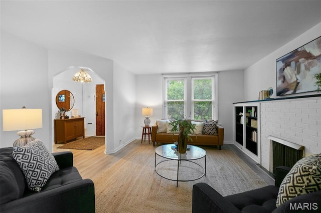 4950 Eichelberger St, Saint Louis, MO 63109 - living room with light wood-style flooring, a brick fireplace, a chandelier, and arched walkways