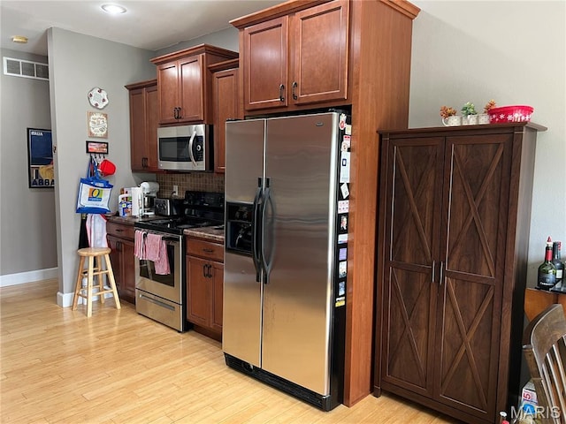 306 Traci Dawn Dr, Rolla, MO 65401 - kitchen with stainless steel appliances, backsplash, light wood-style floors, dark countertops, and recessed lighting