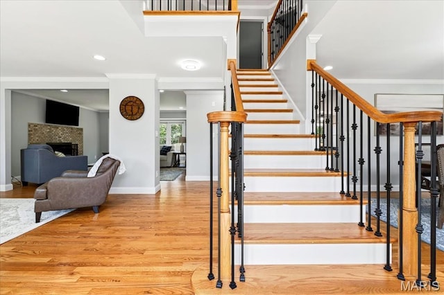 16544 Willow Glen Dr, Wildwood, MO 63040 - staircase featuring wood finished floors, crown molding, a fireplace, and recessed lighting