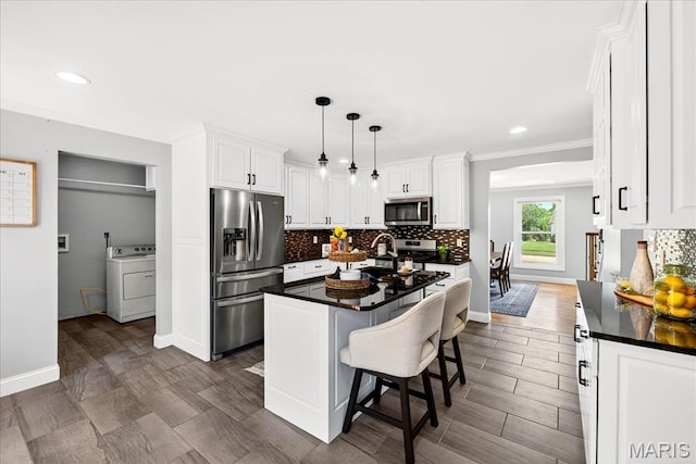 16544 Willow Glen Dr, Wildwood, MO 63040 - kitchen with stainless steel appliances, washer / dryer, dark countertops, tasteful backsplash, and white cabinets