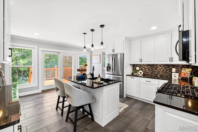 16544 Willow Glen Dr, Wildwood, MO 63040 - kitchen with appliances with stainless steel finishes, white cabinetry, crown molding, a kitchen bar, and decorative backsplash
