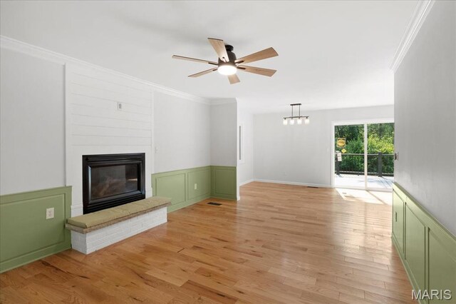 15371 Timber Hill Ln, Chesterfield, MO 63017 - unfurnished living room featuring a ceiling fan, ornamental molding, a large fireplace, light wood finished floors, and a wainscoted wall