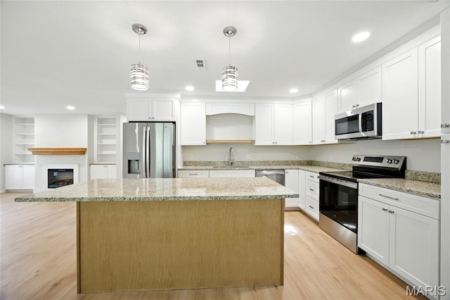 6905 Scenic View Dr, Cedar Hill, MO 63016 - kitchen featuring stainless steel appliances, a kitchen island, light wood-style flooring, white cabinetry, and decorative light fixtures