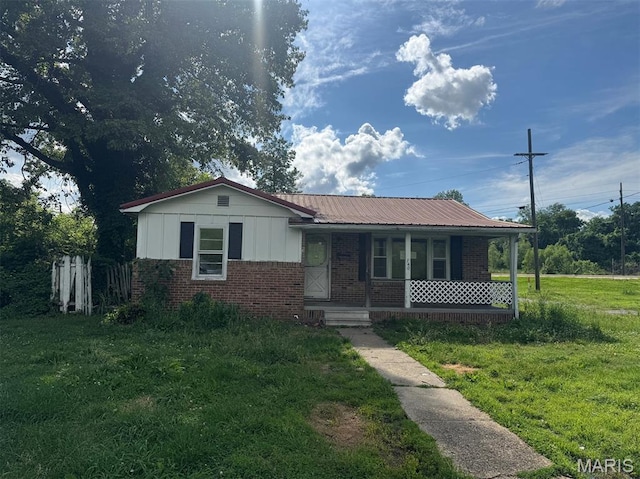 340 S Kitchen St, Dexter, MO 63841 - ranch-style house with brick siding, covered porch, board and batten siding, a front yard, and a metal roof