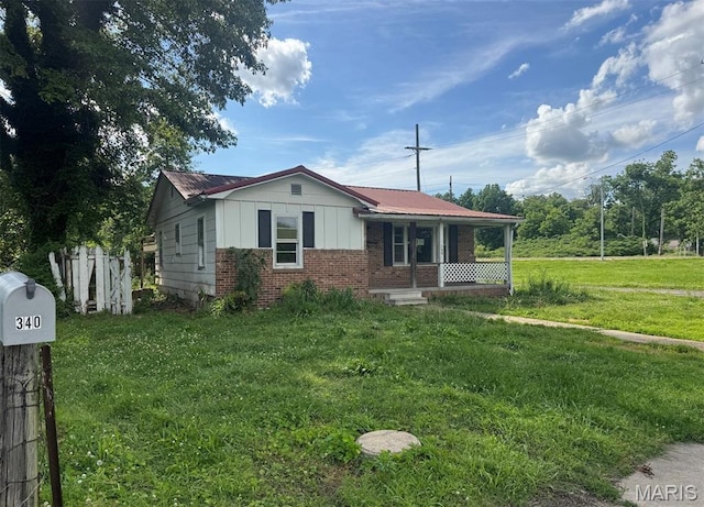 340 S Kitchen St, Dexter, MO 63841 - view of front facade featuring brick siding, a porch, board and batten siding, and a front lawn