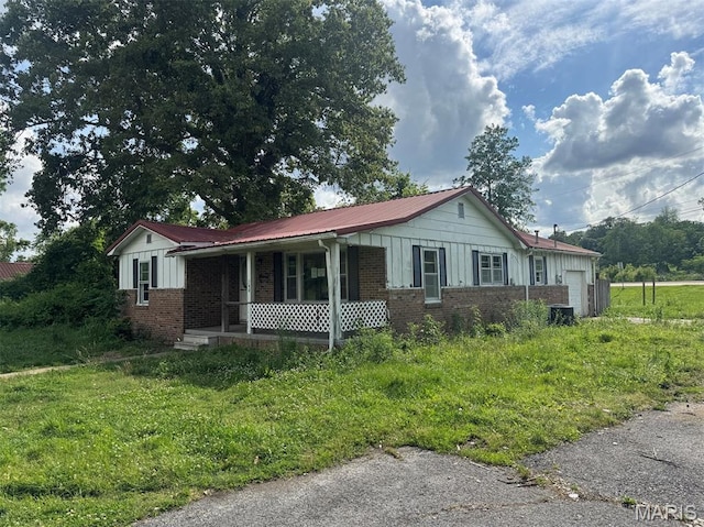 340 S Kitchen St, Dexter, MO 63841 - ranch-style home with covered porch, brick siding, board and batten siding, a garage, and a metal roof