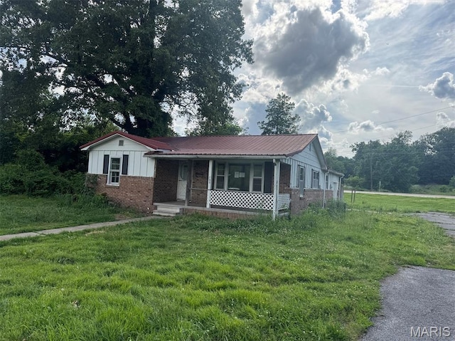 340 S Kitchen St, Dexter, MO 63841 - view of front facade featuring brick siding, a porch, a front yard, a metal roof, and board and batten siding