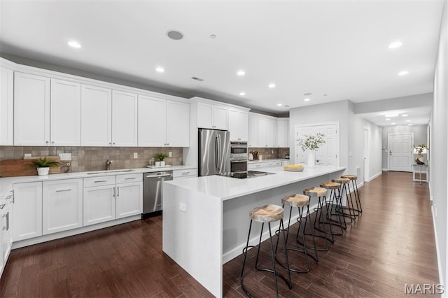 110 N Newstead Ave Unit 303, Saint Louis, MO 63108 - kitchen featuring appliances with stainless steel finishes, white cabinets, a kitchen breakfast bar, and recessed lighting