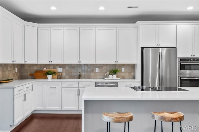 110 N Newstead Ave Unit 303, Saint Louis, MO 63108 - kitchen with stainless steel appliances, a kitchen bar, white cabinetry, and recessed lighting