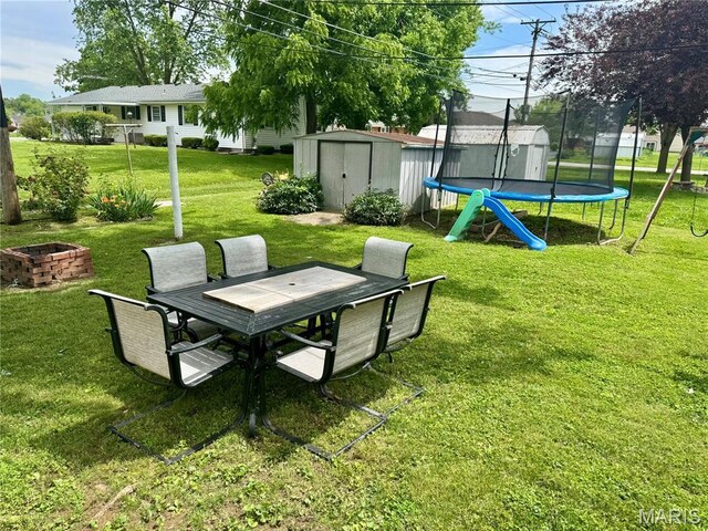 1311 W Line St, Palmyra, MO 63461 - view of grassy yard featuring a storage shed, a trampoline, outdoor dining space, and an outdoor fire pit