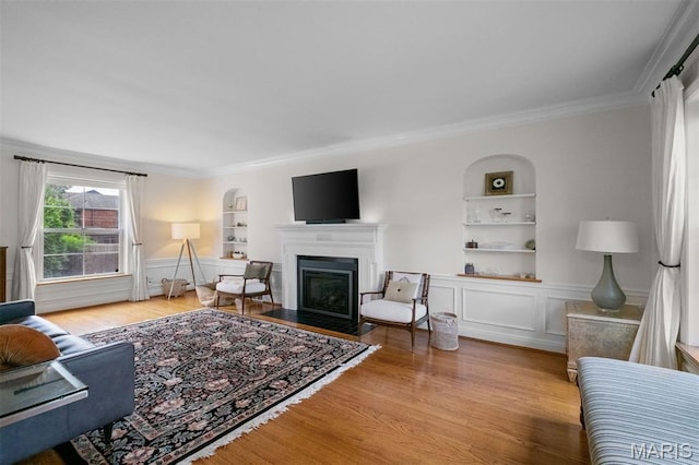 8140 Pershing Ave, Clayton, MO 63105 - living area featuring built in features, crown molding, wood finished floors, a fireplace with flush hearth, and a wainscoted wall