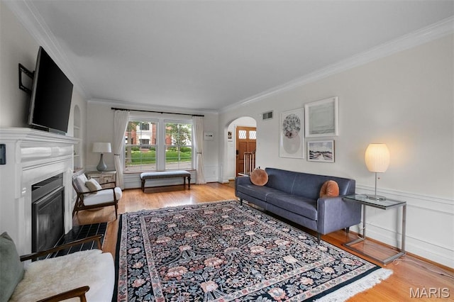 8140 Pershing Ave, Clayton, MO 63105 - living area featuring arched walkways, ornamental molding, wood finished floors, a fireplace with flush hearth, and wainscoting