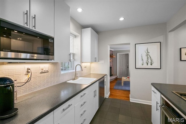 8140 Pershing Ave, Clayton, MO 63105 - kitchen with appliances with stainless steel finishes, dark tile patterned flooring, backsplash, dark countertops, and white cabinets