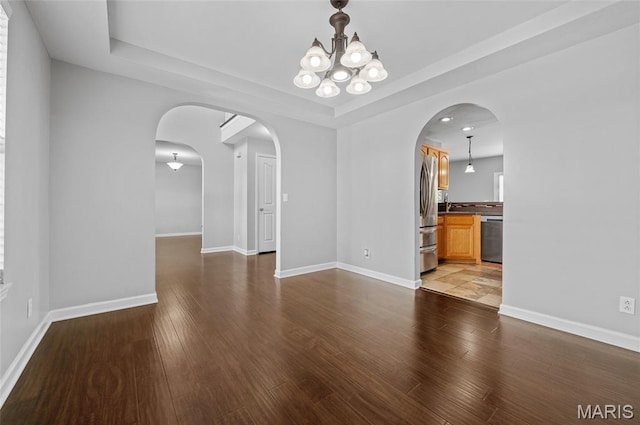 201 Mcclelland Dr, Troy, IL 62294 - empty room with arched walkways, a raised ceiling, a chandelier, and wood finished floors