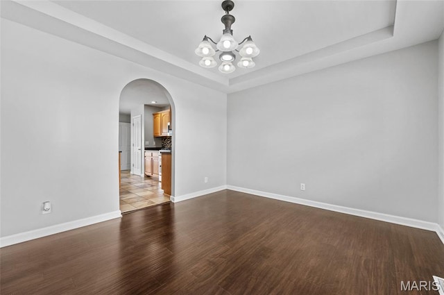 201 Mcclelland Dr, Troy, IL 62294 - spare room with a chandelier, a raised ceiling, arched walkways, and wood finished floors
