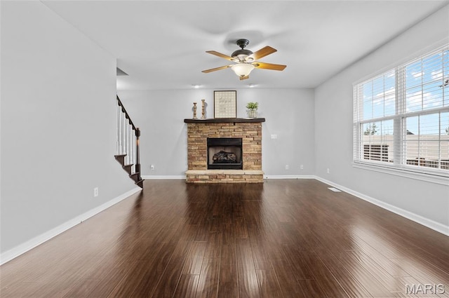 201 Mcclelland Dr, Troy, IL 62294 - unfurnished living room featuring stairs, dark wood-type flooring, a stone fireplace, and ceiling fan