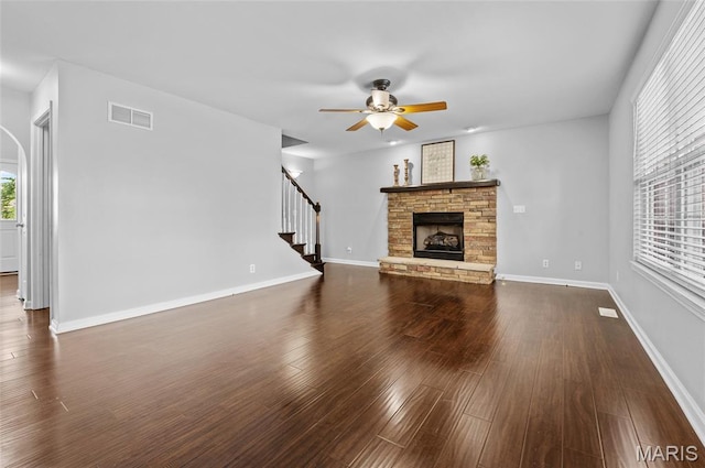 201 Mcclelland Dr, Troy, IL 62294 - unfurnished living room featuring ceiling fan, a stone fireplace, stairway, and dark wood-style flooring