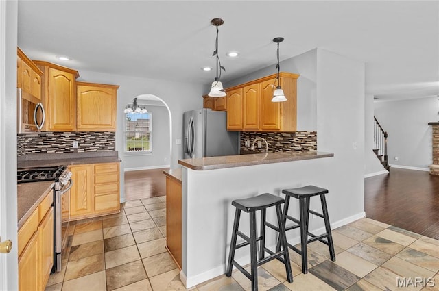 201 Mcclelland Dr, Troy, IL 62294 - kitchen with appliances with stainless steel finishes, backsplash, a kitchen bar, arched walkways, and recessed lighting