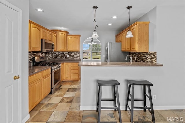 201 Mcclelland Dr, Troy, IL 62294 - kitchen with appliances with stainless steel finishes, backsplash, a kitchen bar, a peninsula, and recessed lighting