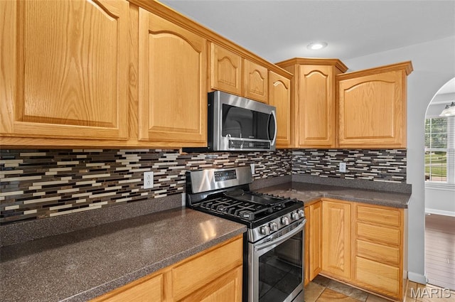 201 Mcclelland Dr, Troy, IL 62294 - kitchen featuring appliances with stainless steel finishes, dark countertops, tasteful backsplash, and arched walkways